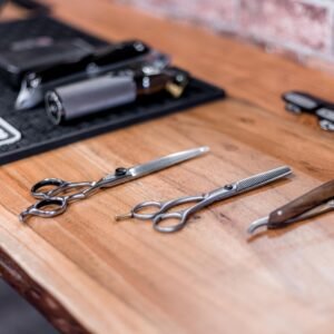 High-quality barber tools arranged on a rustic wooden table in a modern salon.
