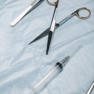 Close-up of surgical scissors, tweezers, and syringe on sterile drapes.